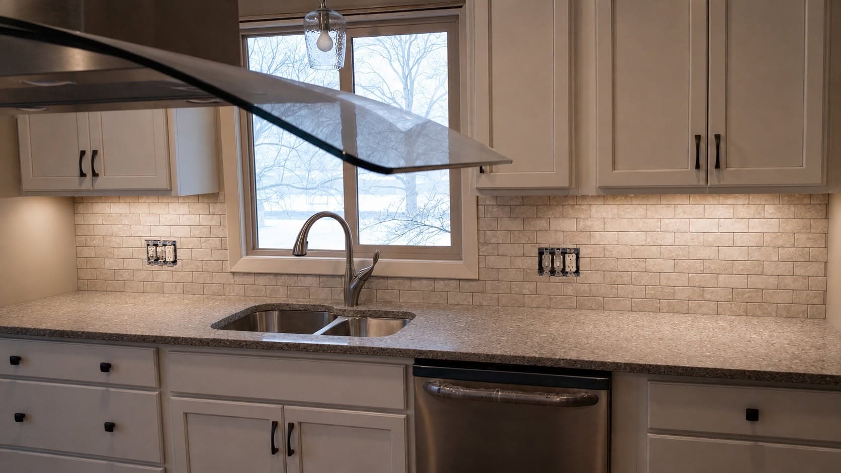 Modern kitchen with light cabinets, brick backsplash, dark countertop, and window with black accents