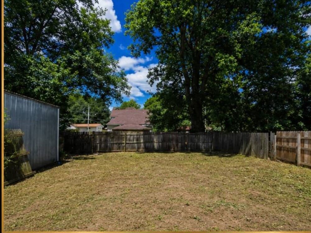 The same backyard lot cleared, leveled, and freshly mowed after cleanup